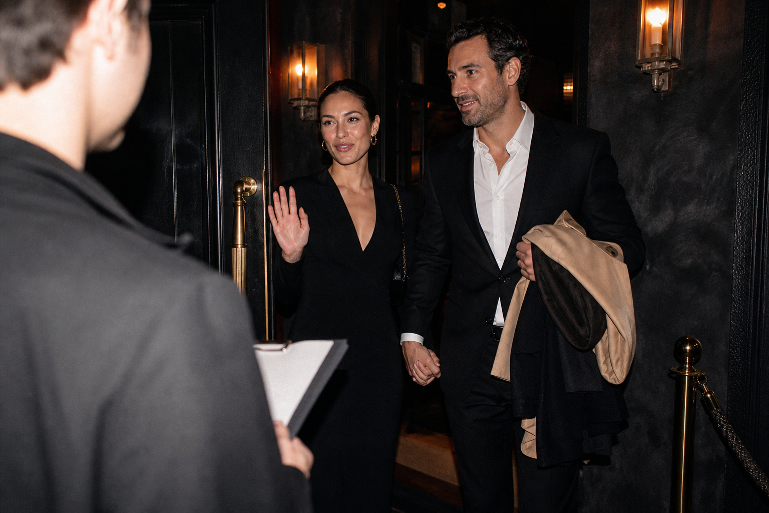 A couple in a dim private lounge at night, holding drinks and turned toward each other in quiet conversation, warm flash-lit atmosphere